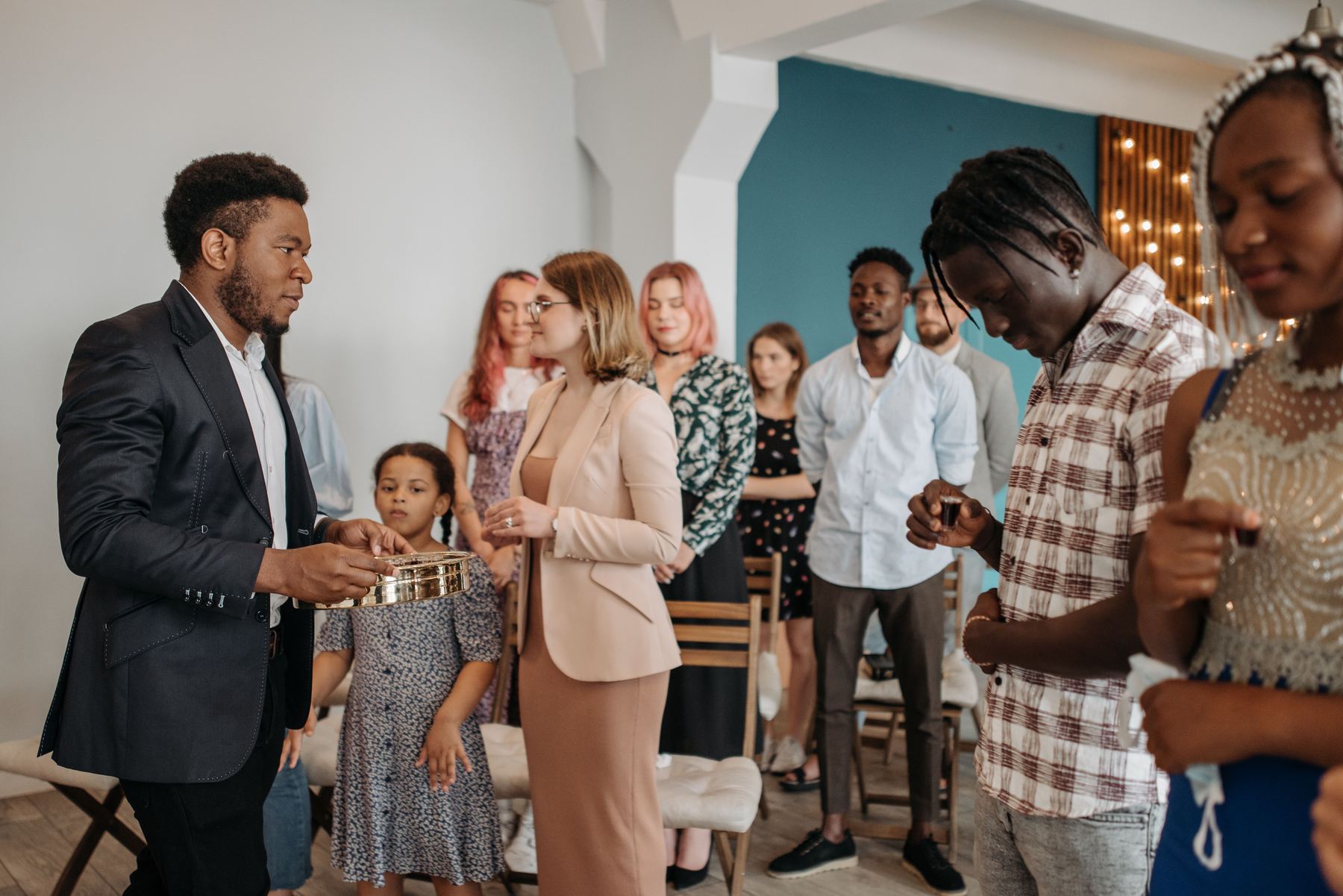 A community group gathered together, sharing communion in a bright room